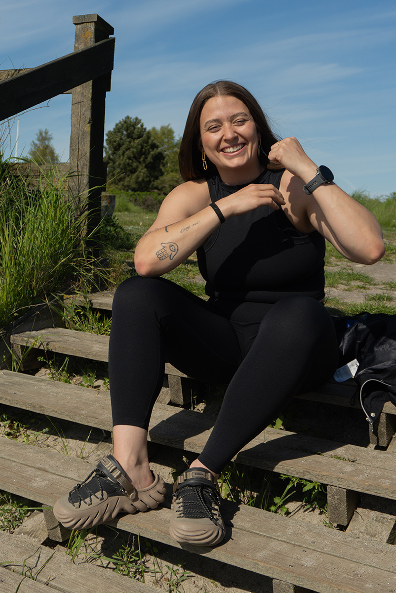 Træneren sidder på trætrin og knytter næven smilende.